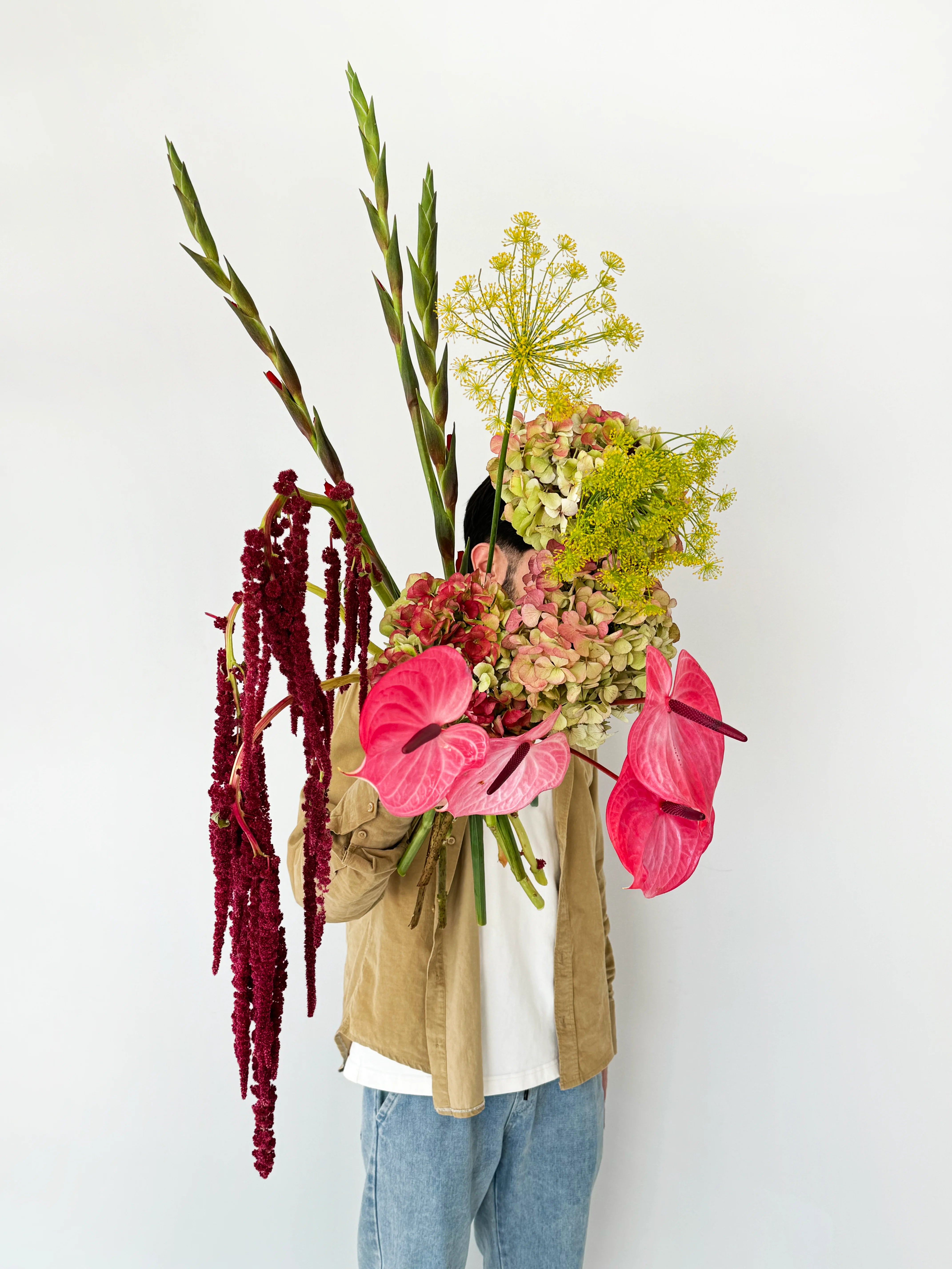 Flower delivery in Dubai: A large bouquet with pink anthuriums, green hydrangeas, yellow dill flowers, red amaranthus, and tall gladiolus stems