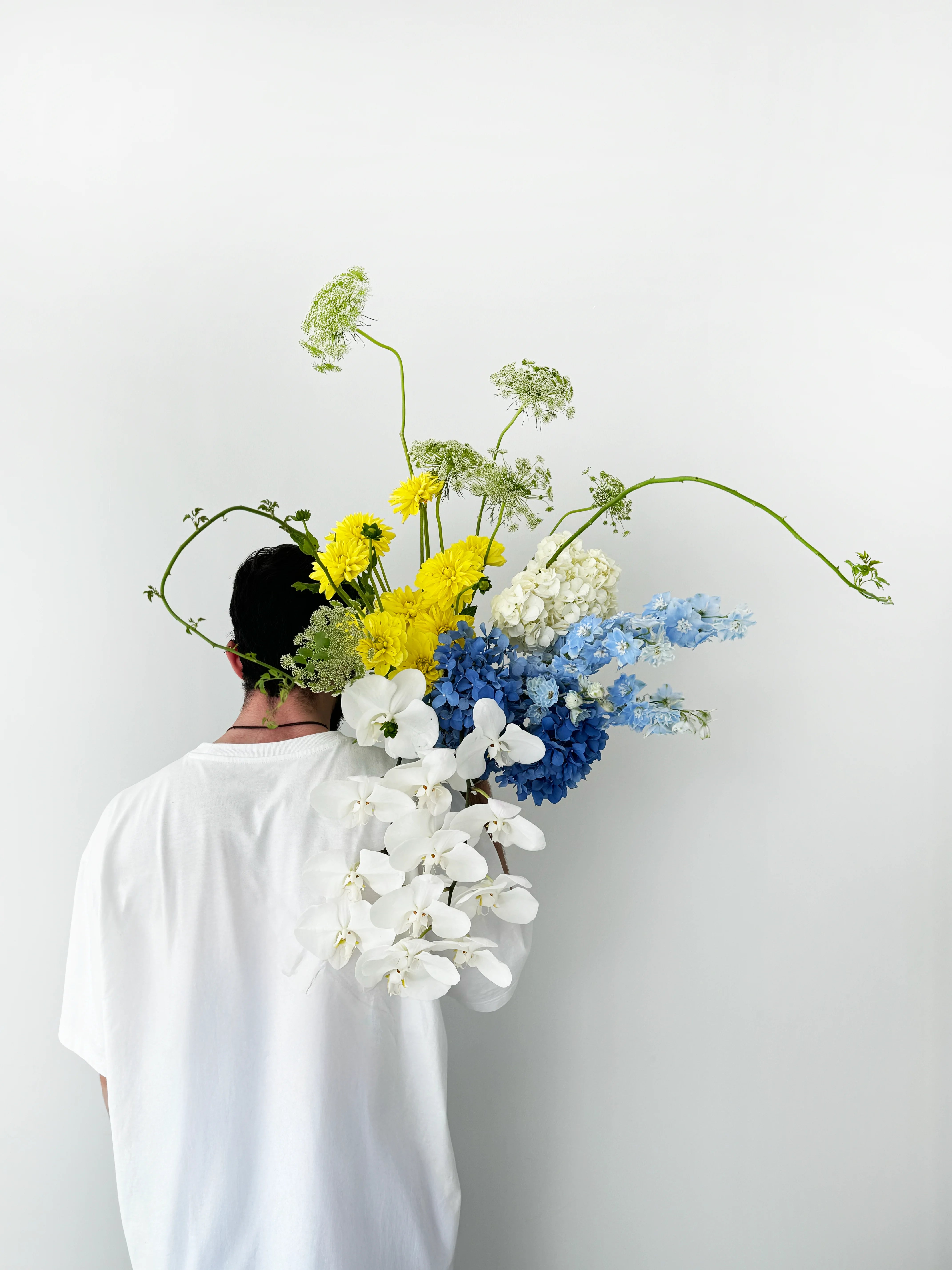 Flower delivery in Dubai: A large bouquet with white orchids, blue hydrangeas, yellow daisies, and green queen anne’s lace